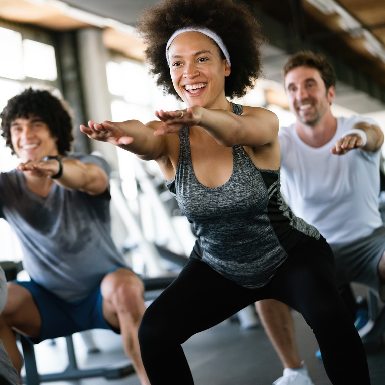  happy fit people at the gym exercising
